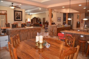A spacious kitchen with wooden cabinetry, a large island with a sink, and a dining area with a wooden table and chairs.