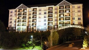 Een hotel met meerdere verdiepingen, balkons, een afsluitbare ingang en een goed verlichte gevel.