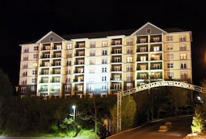 Un hotel de varios pisos con balcones, entrada protegida por una reja y fachada bien iluminada.