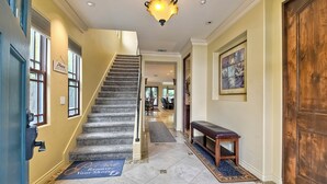 A grand staircase leading to a second floor, a wooden bench, a door, and a hallway with a rug. - 5 Star, Large, Luxury Condo in Carlsbad Village (Carlsbad)