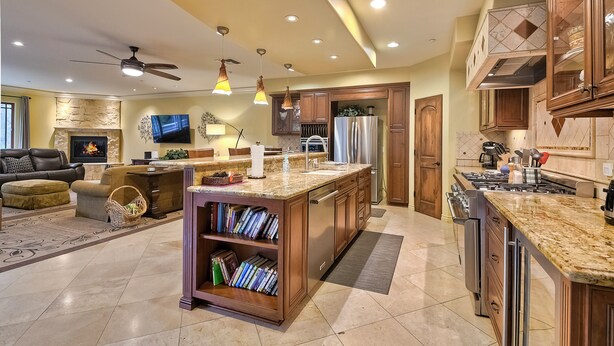 A modern kitchen with a central island, built-in appliances, and a dining area with a sofa and fireplace. - 5 Star, Large, Luxury Condo in Carlsbad Village (Carlsbad)