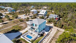 A multi-story house with a pool, surrounded by a forested area. - About Time: Beach Views, Private Pool, Pet-Friendly, Dog Run and Sleeps 14 (Port St. Joe)