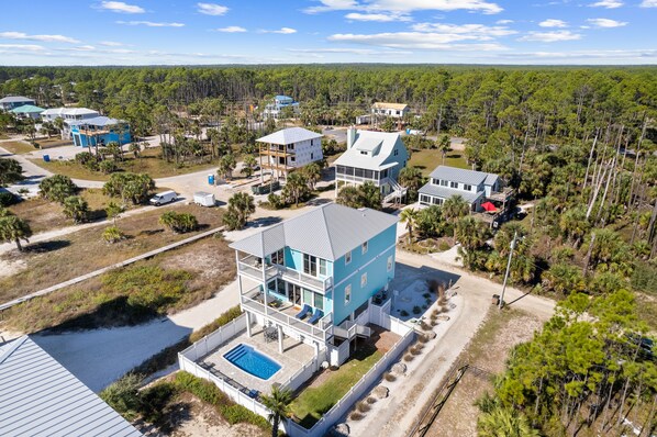 A multi-story house with a pool, surrounded by a forested area.