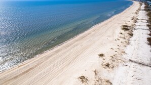 A wide sandy beach with a clear view of the ocean and a distant shoreline. - About Time: Beach Views, Private Pool, Pet-Friendly, Dog Run and Sleeps 14 (Port St. Joe)