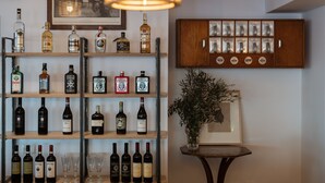 Eine Bar mit Regalen voller Spirituosenflaschen und Gläsern, einem Holzschrank mit Flaschen und einem gerahmten Bild an der Wand.