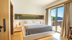 Ein modernes Schlafzimmer mit einem großen Bett, Blick ins Freie und einer Wand mit Musterung über dem Bett.
