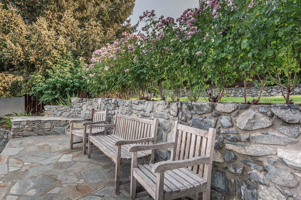 A stone patio with wooden benches and a stone wall.