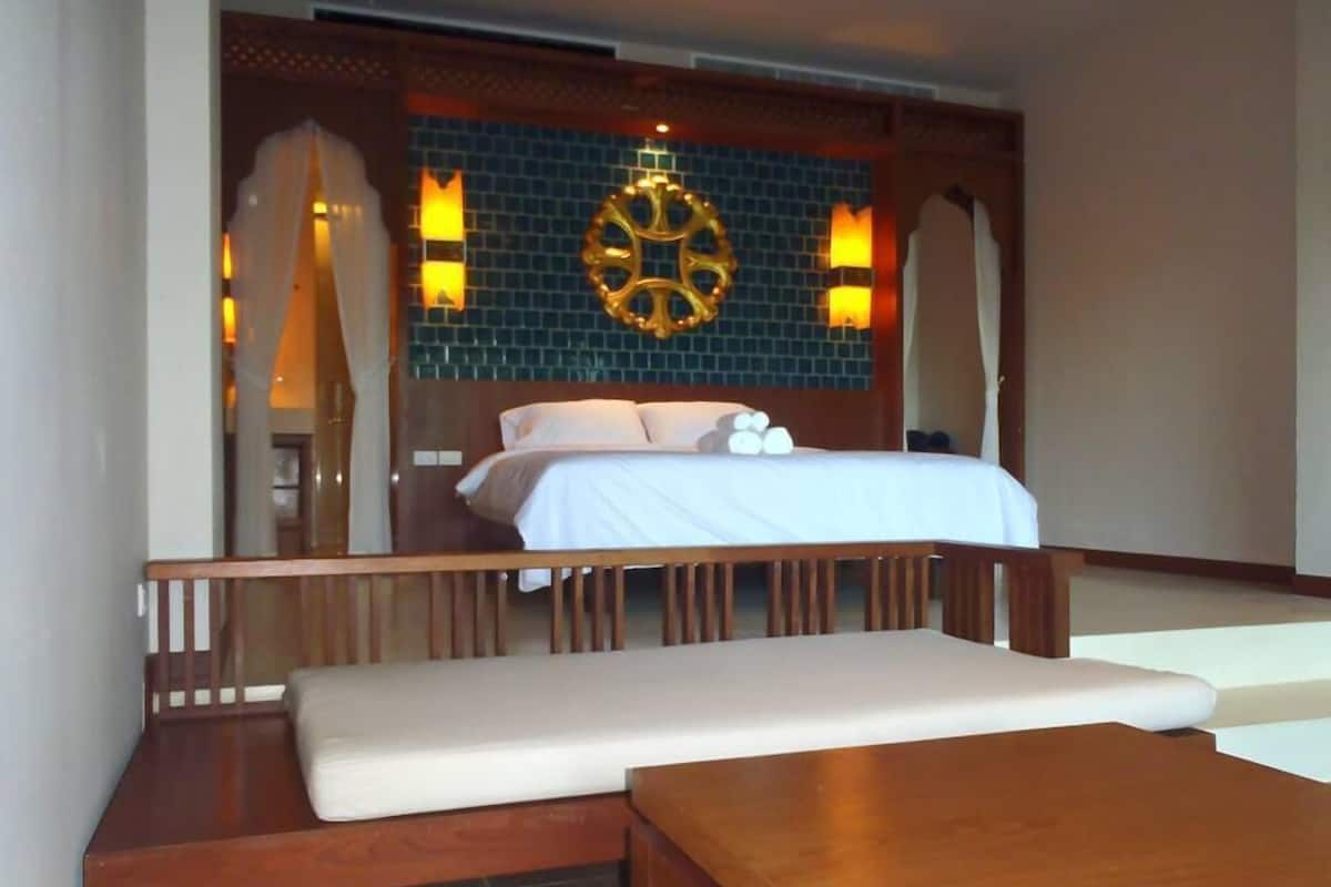 A hotel room with a bed, a wooden bench, and a small table.