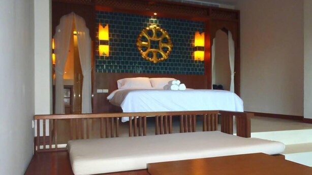 Una habitación de hotel con una cama, un banco de madera y una pequeña mesa.