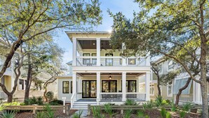 A two-story house with a balcony, surrounded by trees and a landscaped garden. - Stunning WaterColor Retreat: Bikes, WaterColor Beach Club Access, Carriage House, Pure Relaxation! (Santa Rosa Beach)