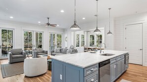 A spacious kitchen with a large island, modern appliances, and ample natural light from large windows. - Stunning WaterColor Retreat: Bikes, WaterColor Beach Club Access, Carriage House, Pure Relaxation! (Santa Rosa Beach)