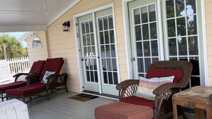 A covered porch with wicker furniture, a ceiling fan, and large windows. - Pelican condo in Chimney Creek (Tybee Island)