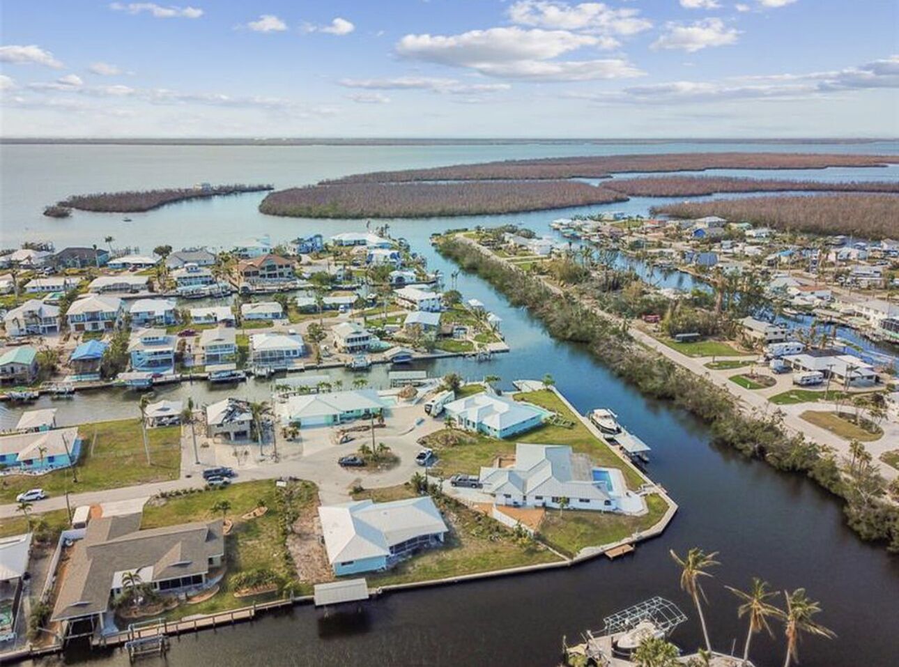 Vista aérea de una zona residencial costera con casas, muelles y un puerto deportivo.