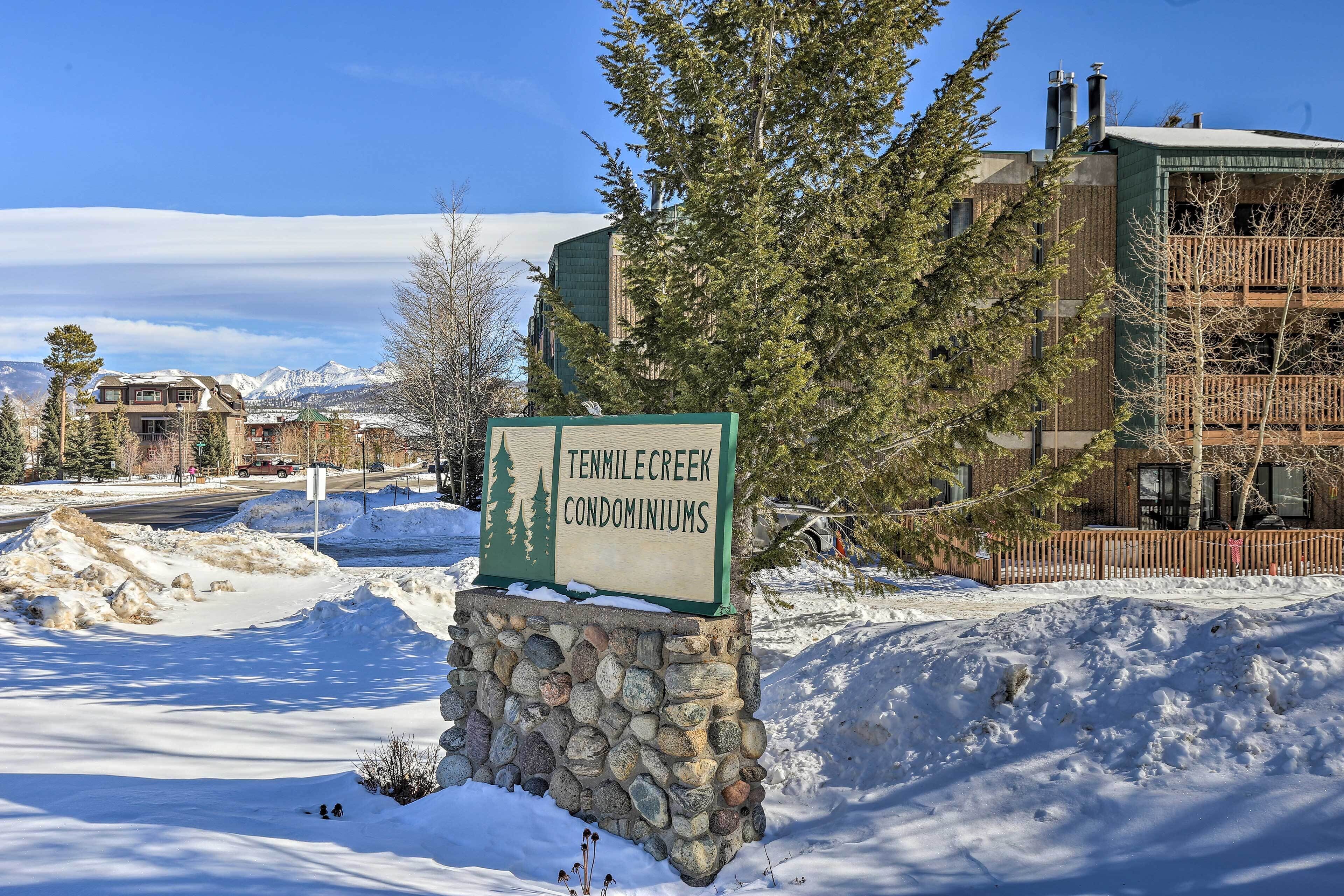 Senyal per als Condominis Tenmile Creek, amb base de pedra, envoltat de neu i arbres.