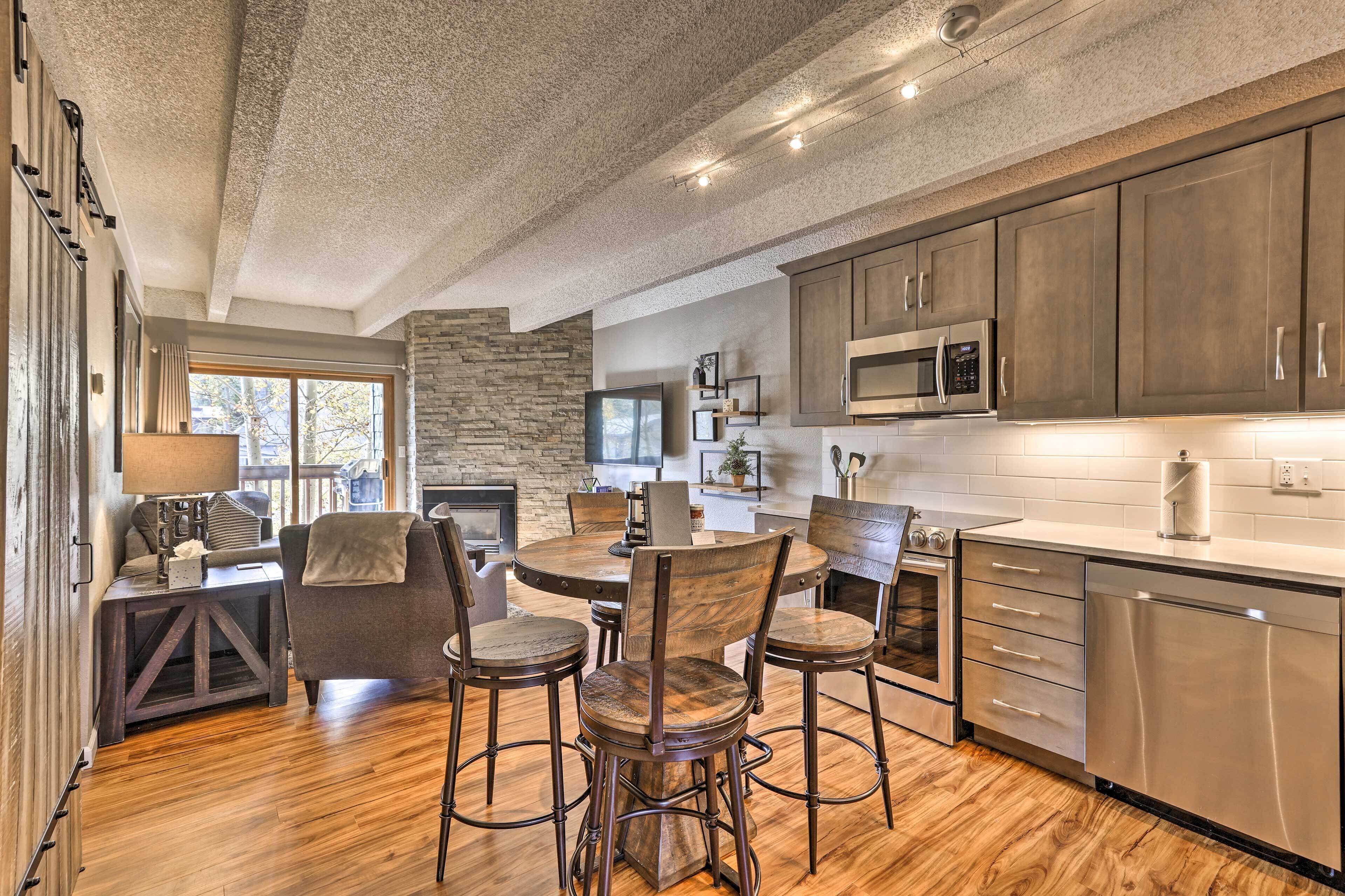 A modern kitchen with wooden flooring, a stone accent wall, and stainless steel appliances.