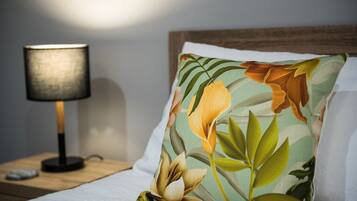 Un lit avec un oreiller à motifs floraux, une lampe de chevet et une table de nuit en bois.