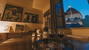 A bar area with a bottle of wine, glasses, and a view of a dome through a window. - Luxury Apartment With Stunning View  (Firenze)