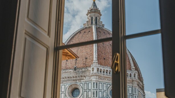 A view through a window of a historic building with a dome and a tall tower. - Luxury Apartment With Stunning View  (Firenze)