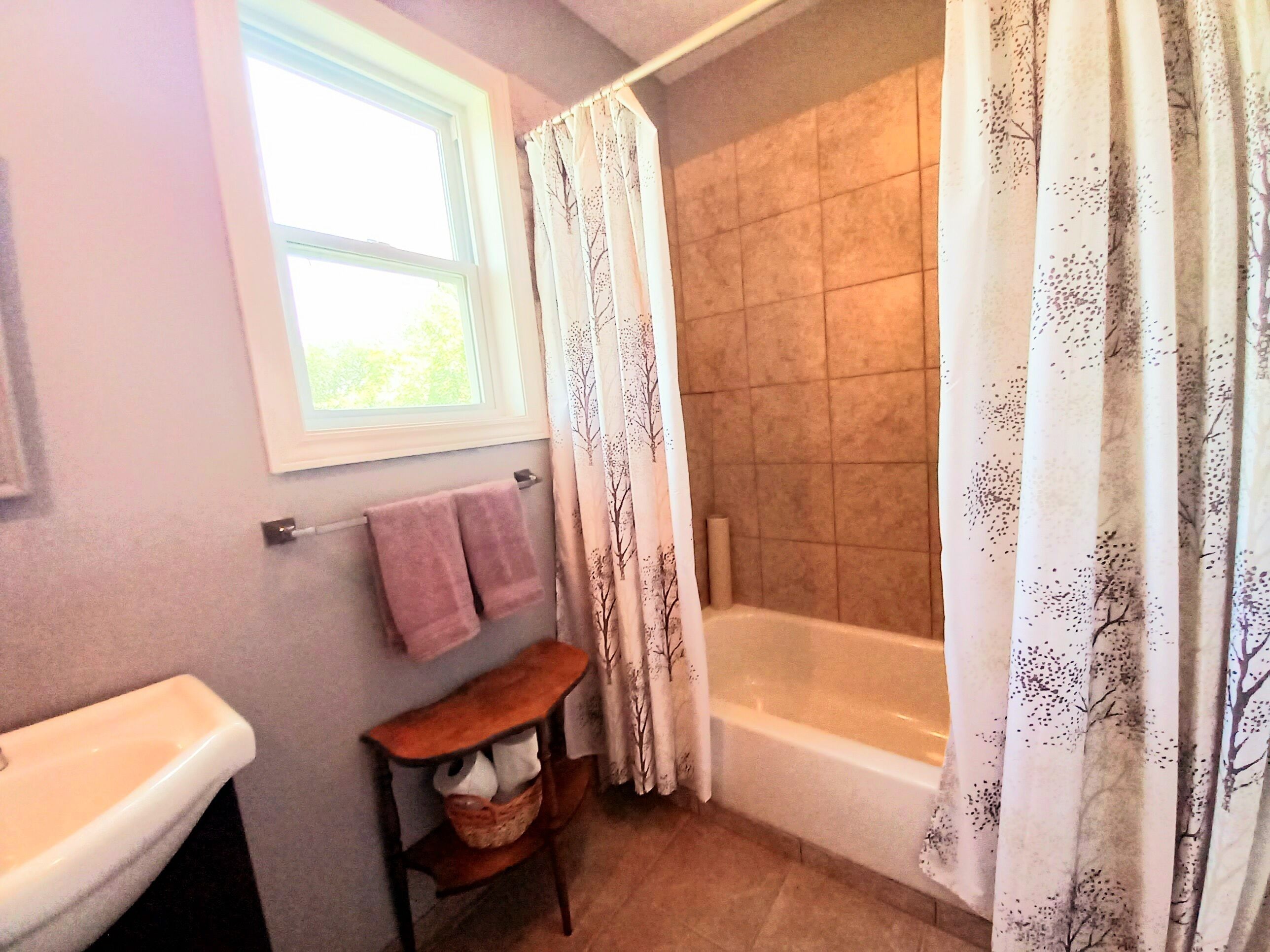 Un baño con bañera, ventana y toallero.