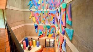 Una escalera con llamativo arte mural geométrico y una pequeña planta en la barandilla.