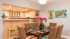 A dining area with a wooden table set for six, surrounded by woven chairs.
