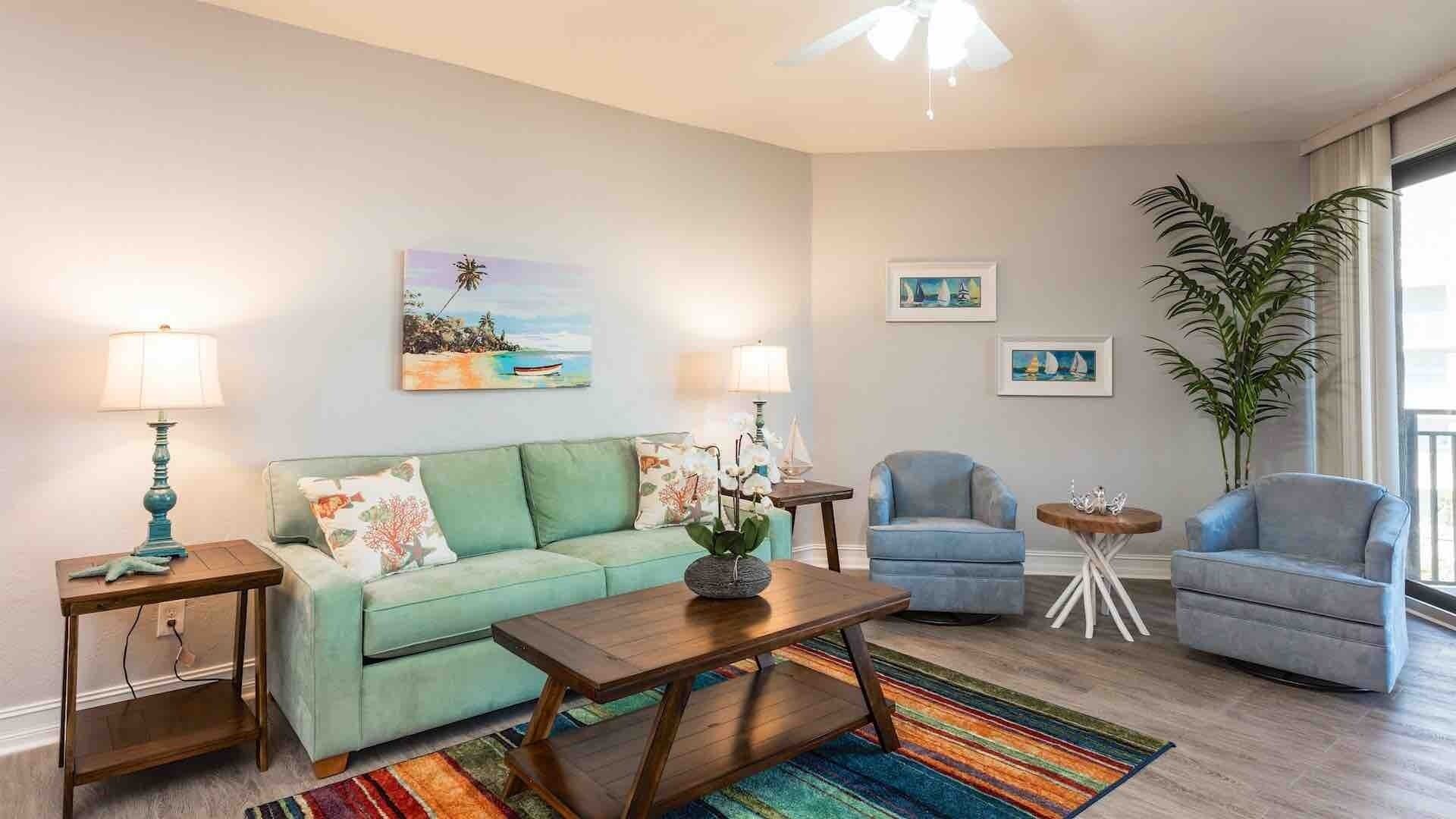 A living room with a sofa, two armchairs, a coffee table, and a rug. There are two lamps, a painting, and a potted plant.