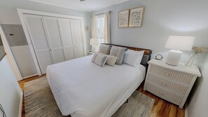 Une chambre à coucher avec un lit, des tables de chevet, une armoire et une fenêtre.