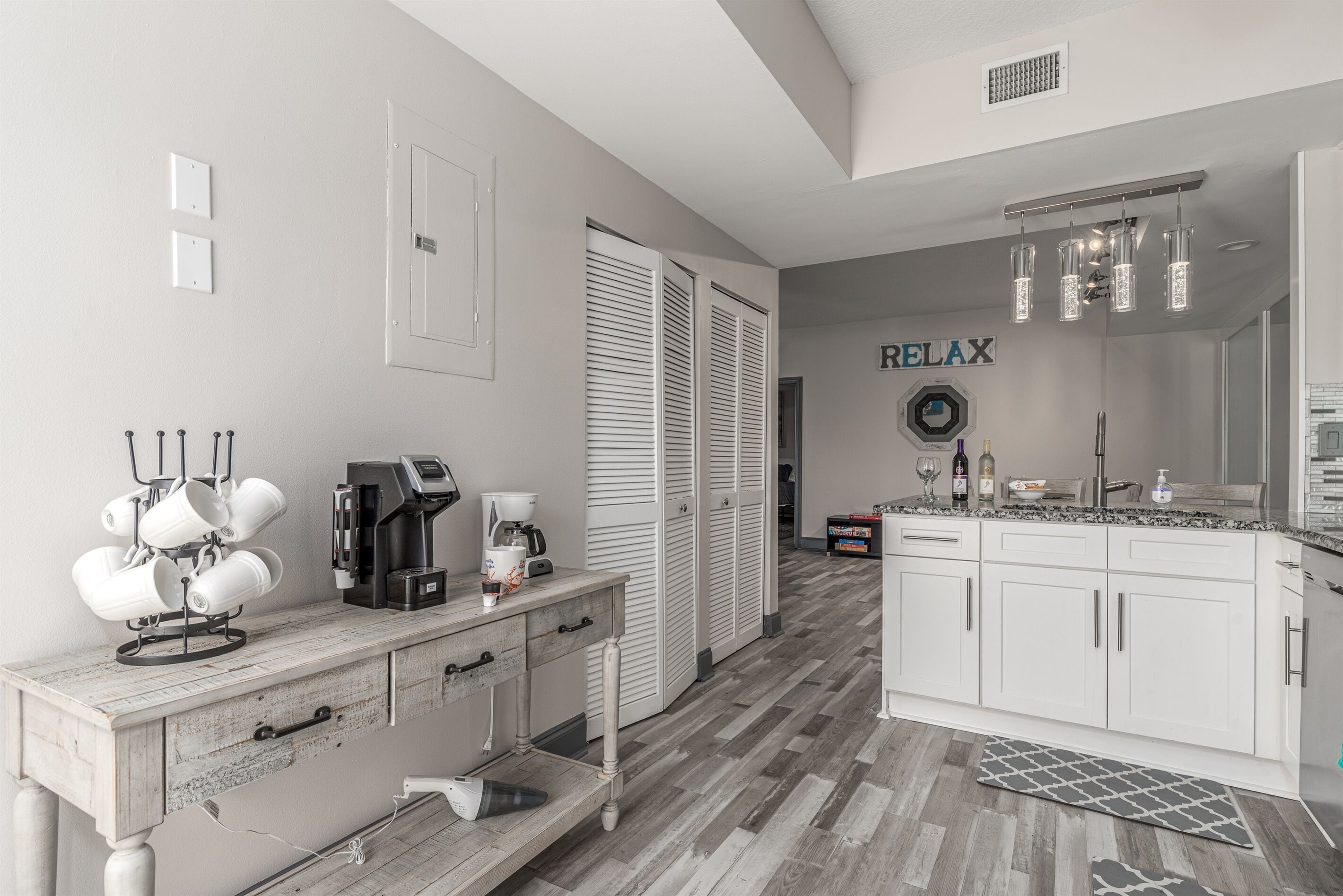A modern kitchen with white cabinets, a coffee machine, and a countertop with a coffee pot.