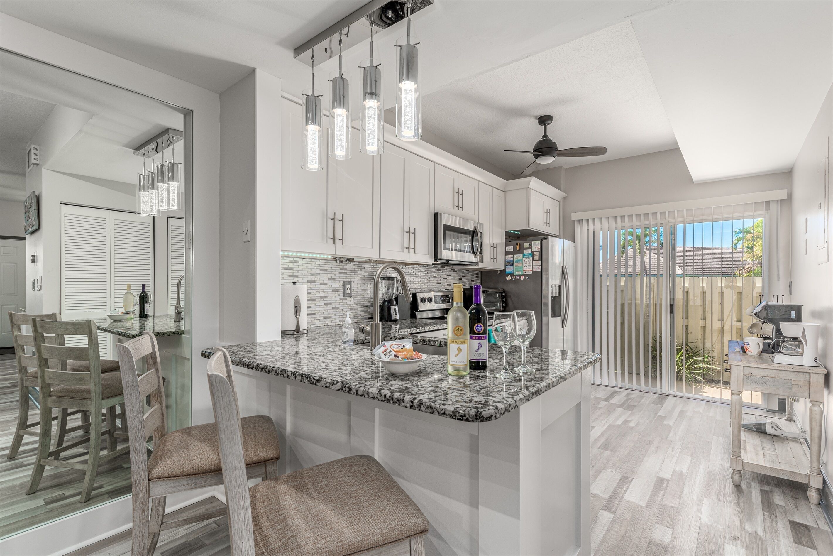 Una cocina moderna con una isla central, electrodomésticos de acero inoxidable y una zona de comedor con sillas de madera.