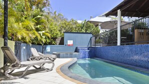 A swimming pool with a tiled edge, lounge chairs, and a covered seating area. - Byron Getaway at Eco Beach (Byron Bay)