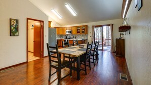 Un comedor amplio con mesa y sillas de madera, una cocina con armarios de madera, y vistas al exterior.