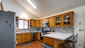 Una cocina con armarios de madera, un refrigerador de acero inoxidable, un microondas, un horno y salpicadero de azulejos.