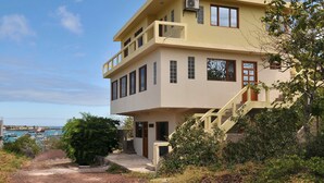 A two-story building with a balcony, a staircase, and a view of the sea.