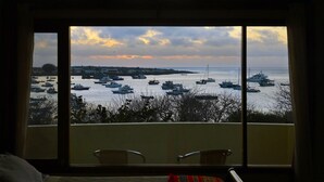 A room with a large window overlooking a marina with numerous boats. There are two chairs in the foreground.