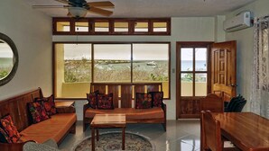 A room with a view of the sea, a ceiling fan, and wooden furniture.
