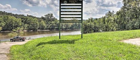 Un cartel con información sobre el acceso al río Blanco, incluyendo un límite diario de 5 truchas, prohibición de armas de fuego cargadas y acampada pernocturna.