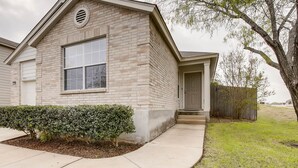 A two-story house with a brick exterior, a large window, and a well-maintained lawn. - BMT Grads Stay! Minutes to Lackland + Pool & Theme Parks (San Antonio)