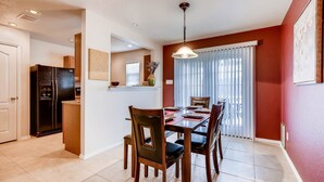 A dining area with a wooden table and chairs, a black refrigerator, and a ceiling light fixture. - BMT Grads Stay! Minutes to Lackland + Pool & Theme Parks (San Antonio)