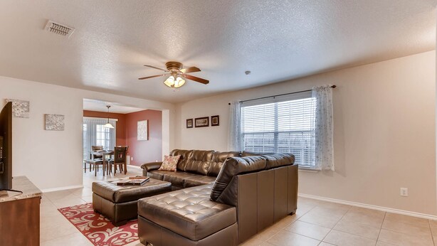 A spacious living room with a sectional sofa, a ceiling fan, and a dining area in the background. - BMT Grads Stay! Minutes to Lackland + Pool & Theme Parks (San Antonio)