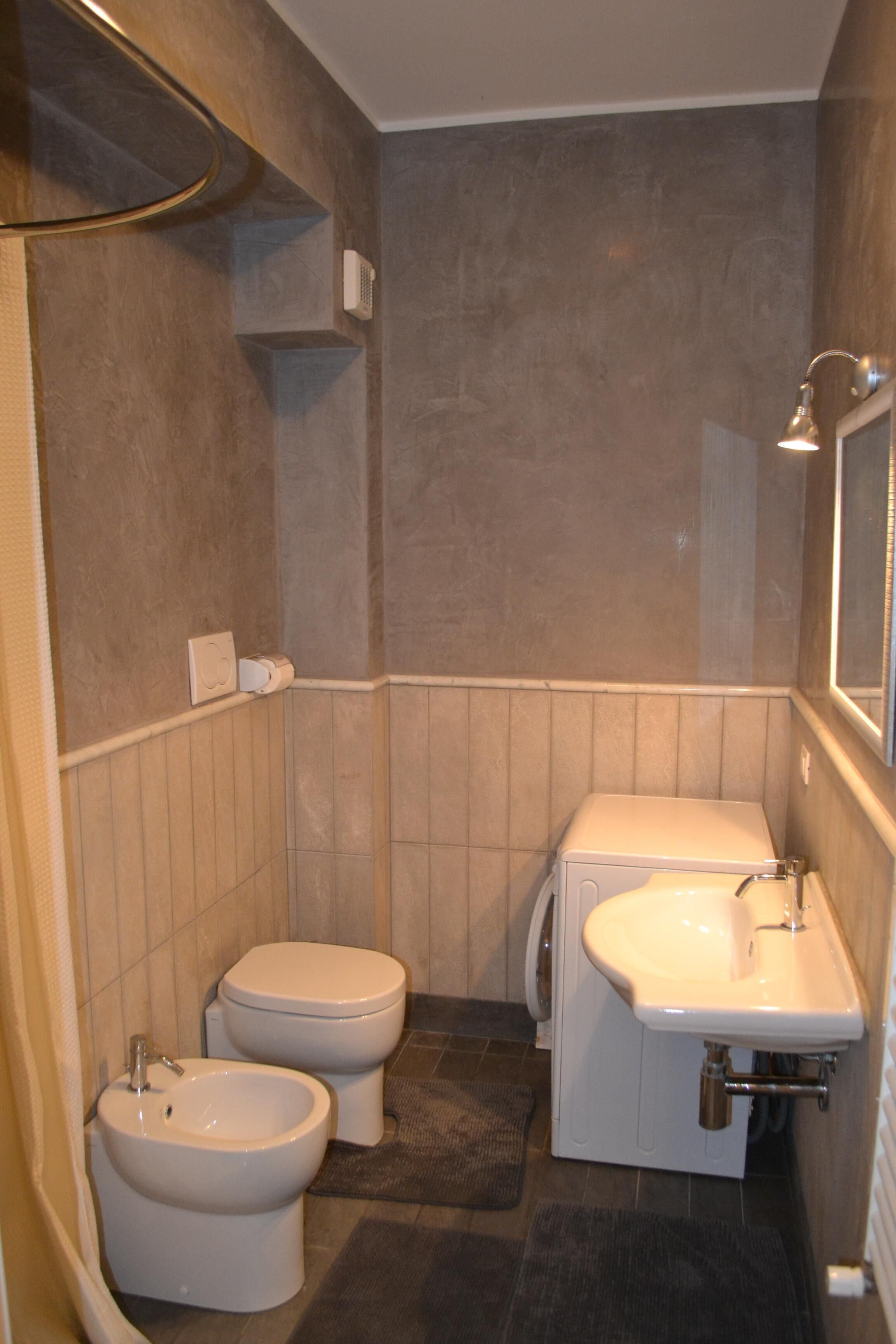 Een badkamer met twee toiletten, een hygiëneschuimer en een wastafel.