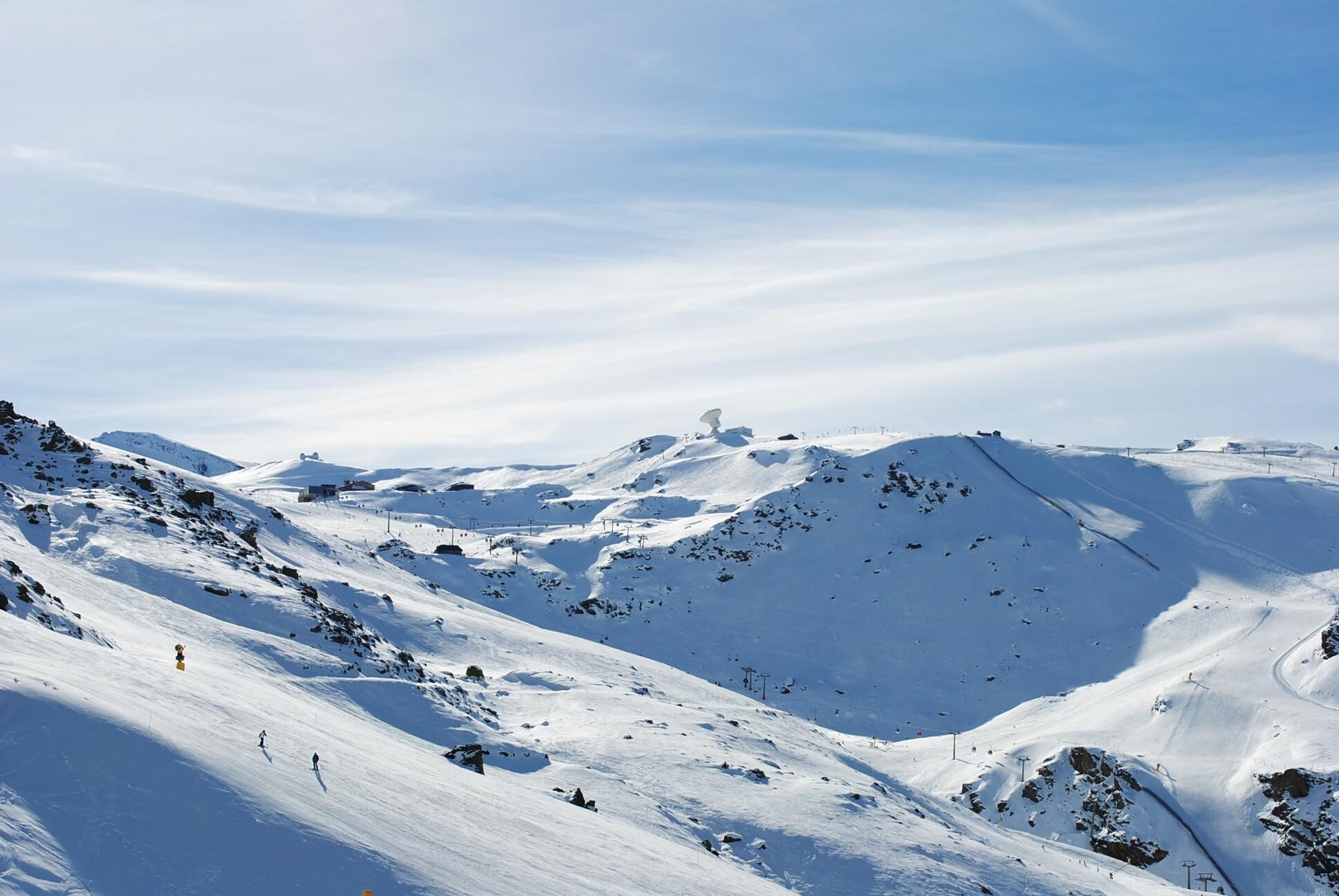 Een besneeuwd berglandschap met skipistes en een stoeltjeslift.