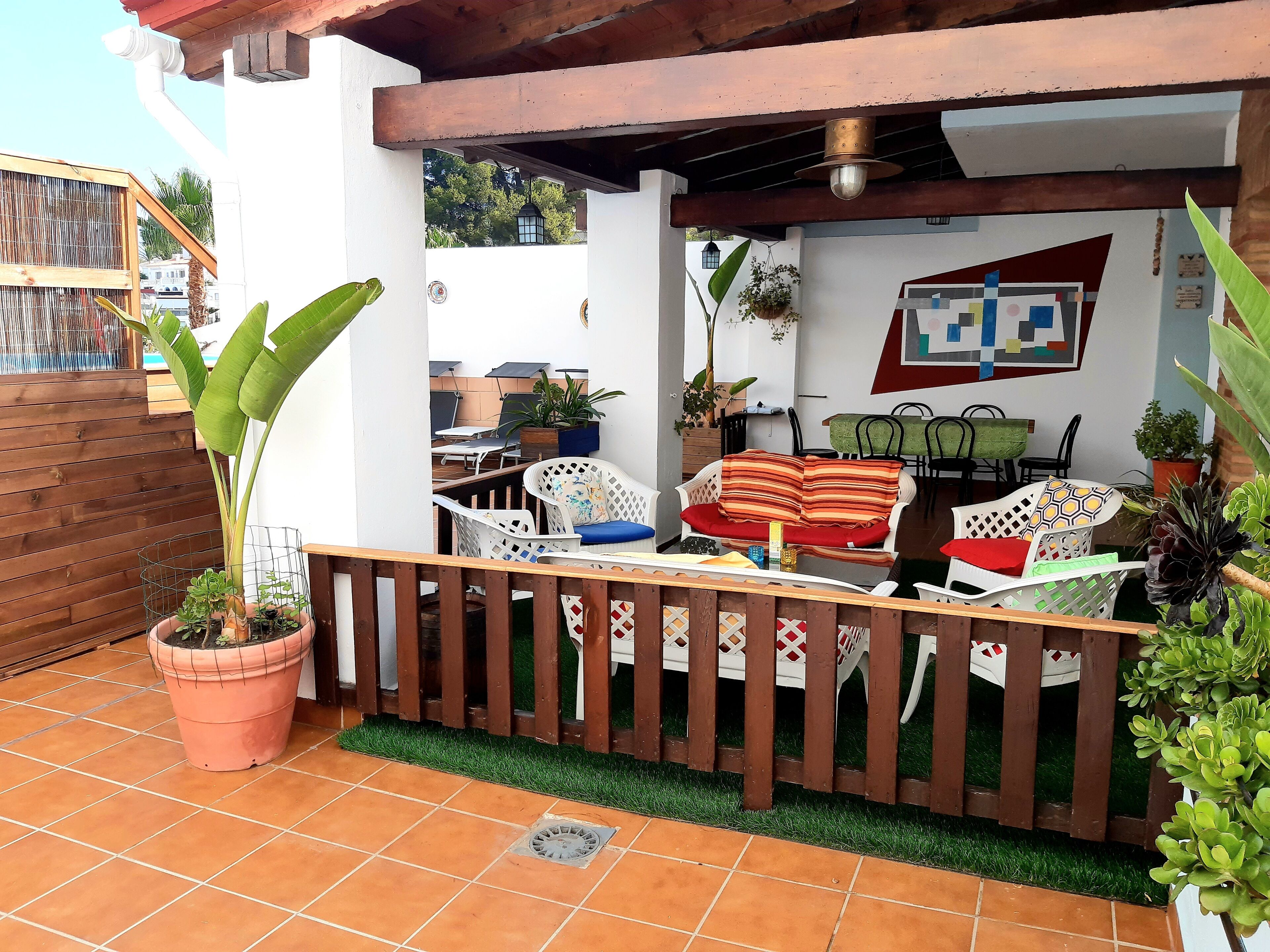 Un patio con cerramiento de madera, plantas en macetas y mobiliario exterior.