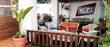 Un patio con cerramiento de madera, plantas en macetas y mobiliario exterior.