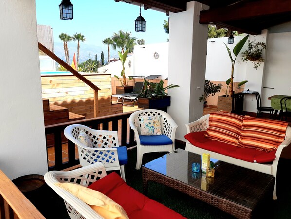A terrace with white wicker furniture, a glass table, and potted plants. - AIR CONDITIONED HOUSE POOL PARKING WIFI NEAR THE CENTER AND BEACH ALMUÑECAR. (Almuñécar)