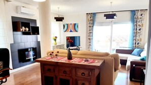 Un salon moderne avec une table basse en bois, un canapé, un téléviseur fixé au mur et une cheminée.