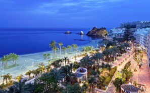A coastal hotel with a beach view, palm trees, and a historic fort. - AIR CONDITIONED HOUSE POOL PARKING WIFI NEAR THE CENTER AND BEACH ALMUÑECAR. (Almuñécar)