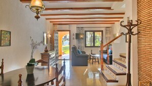 Amplia sala de estar con escalera de madera, mesa de comedor con sillas y sofá.