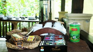 A breakfast setup with tea, snacks, and a coffee pot on a wooden table.