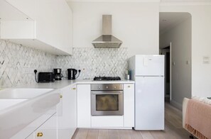 A compact kitchen with white cabinetry, a stainless steel oven, a gas stove, and a white refrigerator.