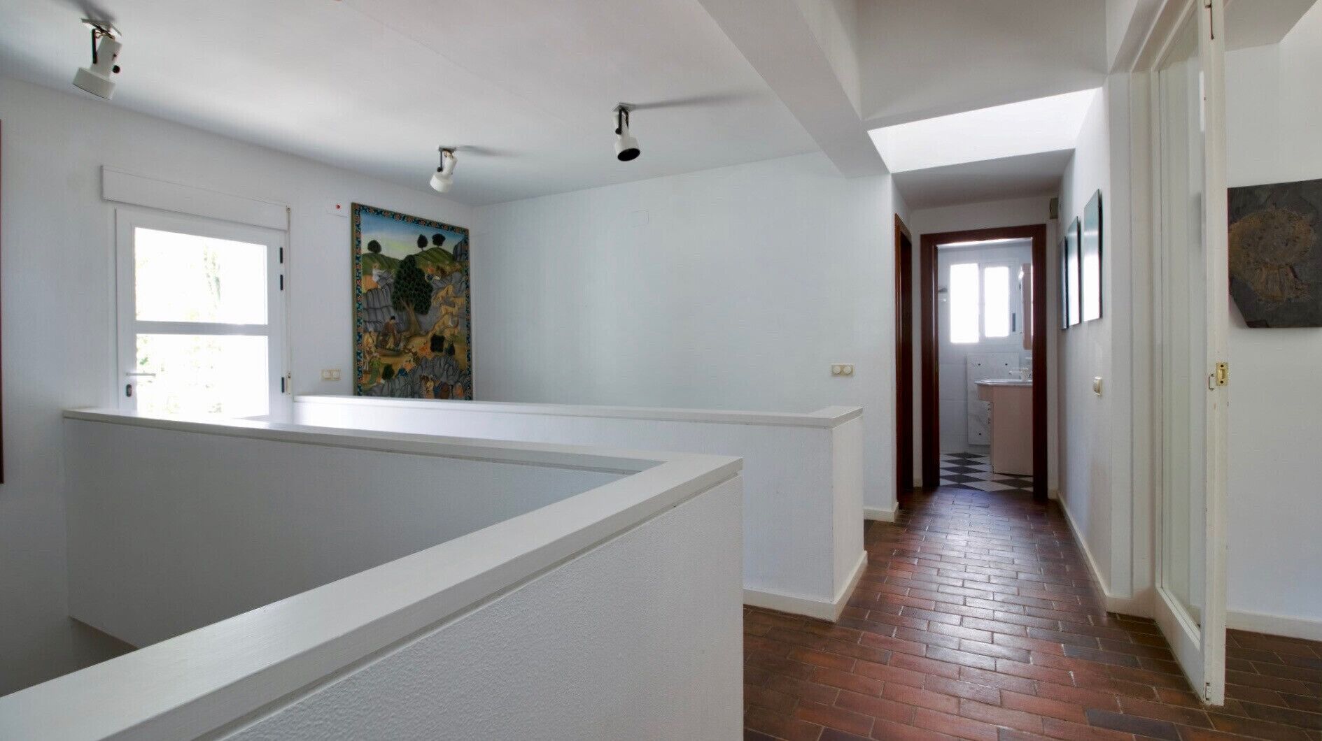 Une pièce spacieuse avec un plafond haut, une grande fenêtre et une vue sur un chemin de briques menant à une salle de bain.